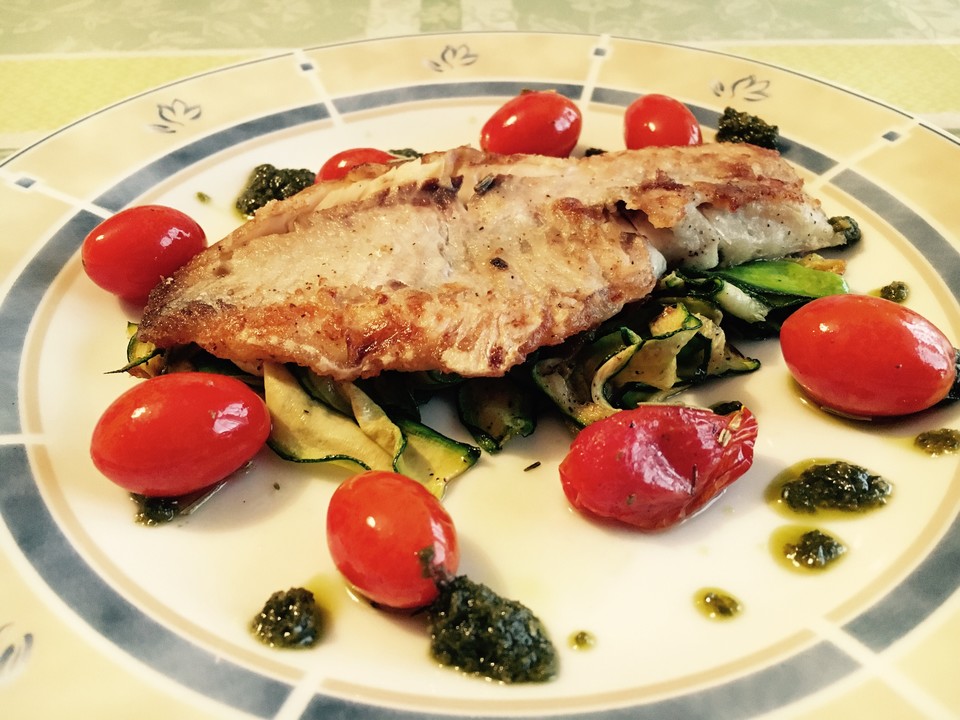 Auf der Haut gebratenes Fischfilet auf gegrillten Zucchinigemüse ...