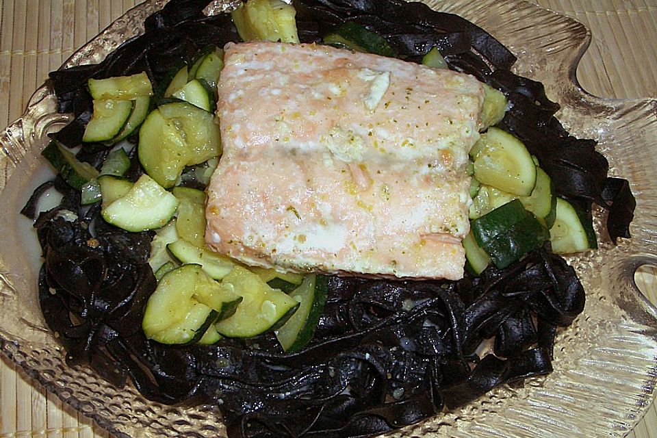 Lachsfilet in einem Bett aus schwarzen Bandnudeln mit Zucchinigemüse