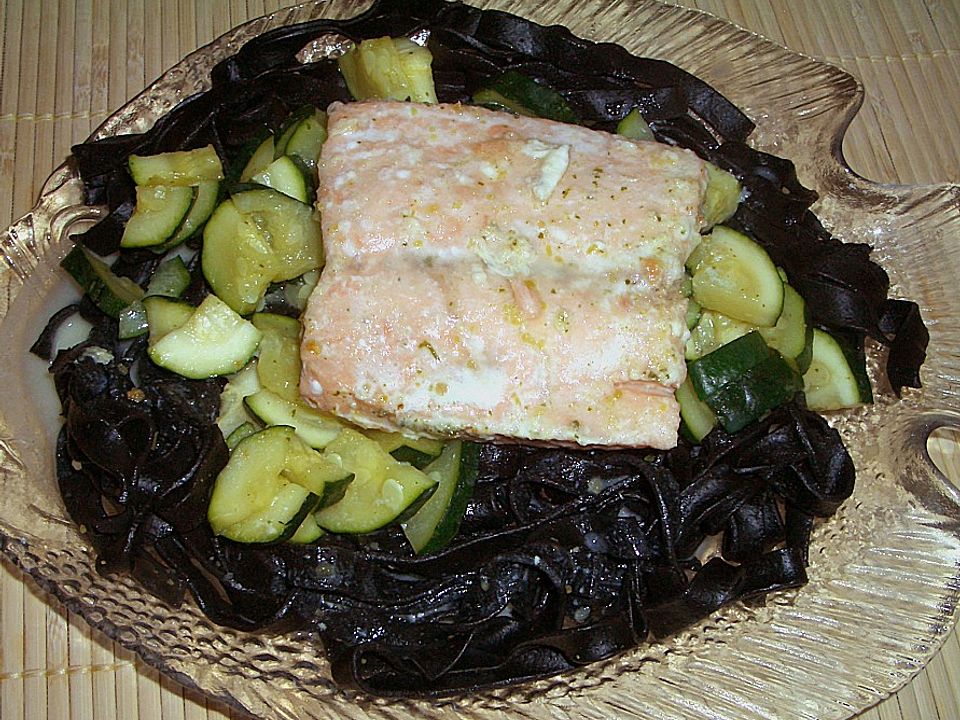 Lachsfilet in einem Bett aus schwarzen Bandnudeln mit Zucchinigemüse ...