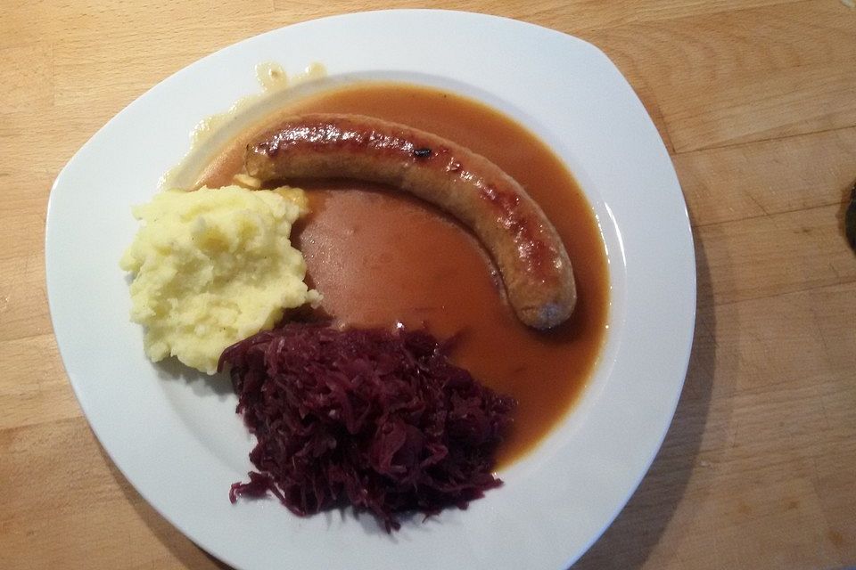 Frische Bratwurst in einer Apfel-Malzbier-Sauce mit Kartoffeln und Rotkohl