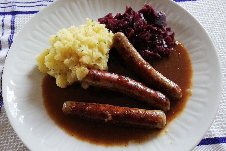 Frische Bratwurst in einer Apfel-Malzbier-Sauce mit Kartoffeln und Rotkohl