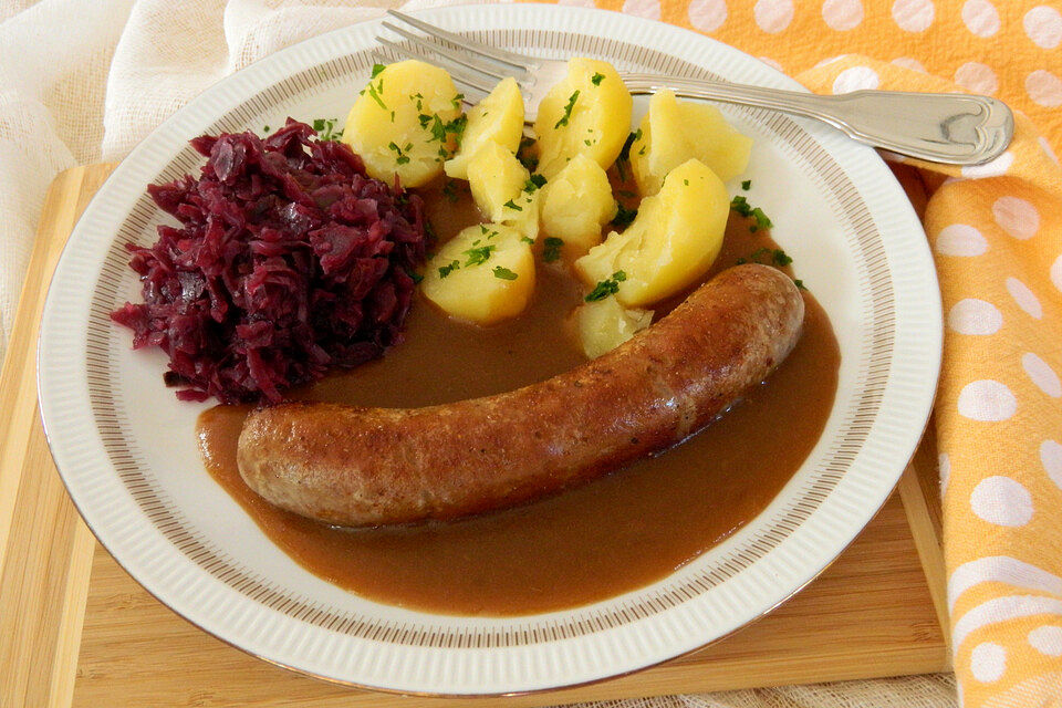 Frische Bratwurst in einer Apfel-Malzbier-Sauce mit Kartoffeln und Rotkohl