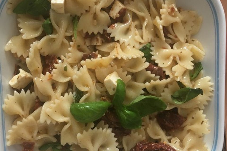 Nudelsalat mit getrockneten Tomaten, Pinienkernen, Schafskäse und Basilikum