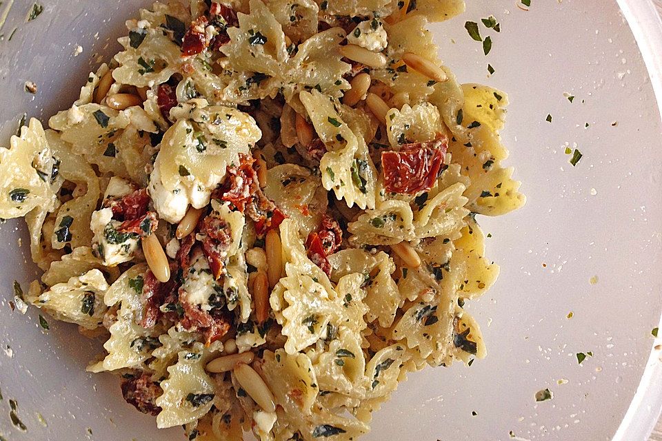 Nudelsalat mit getrockneten Tomaten, Pinienkernen, Schafskäse und Basilikum