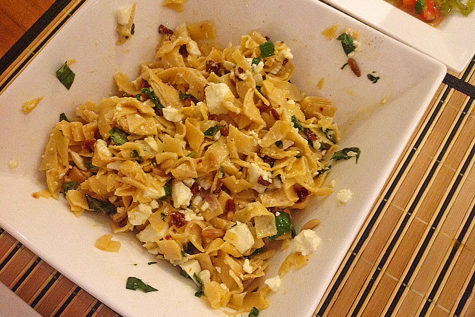 Nudelsalat mit getrockneten Tomaten, Pinienkernen, Schafskäse und Basilikum