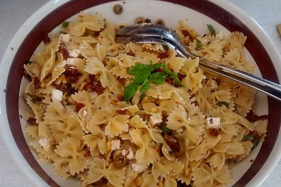 Nudelsalat mit getrockneten Tomaten, Pinienkernen, Schafskäse und Basilikum