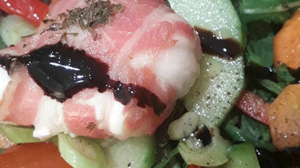 Ziegenweichkäse mit Honig in Bacon auf Feldsalat