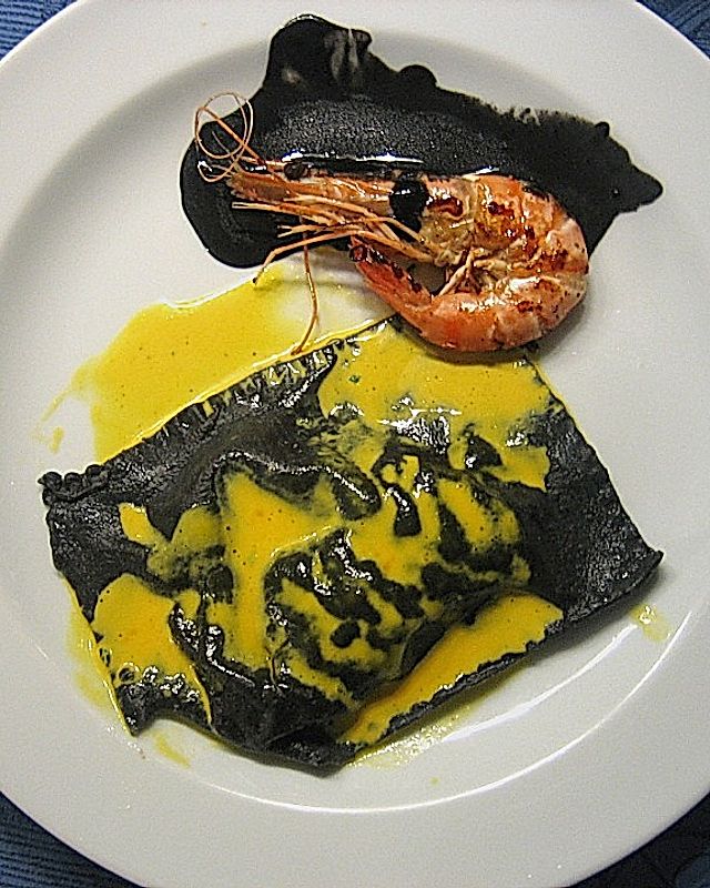 Schwarze Ravioli mit Garnelenfüllung an gelber und schwarzer Sauce