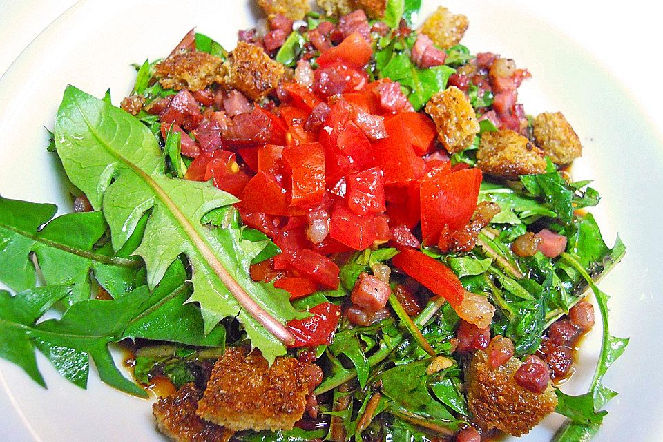 Löwenzahnsalat mit Gänseblümchen und Tomaten-, Speck- und Weißbrotwürfeln