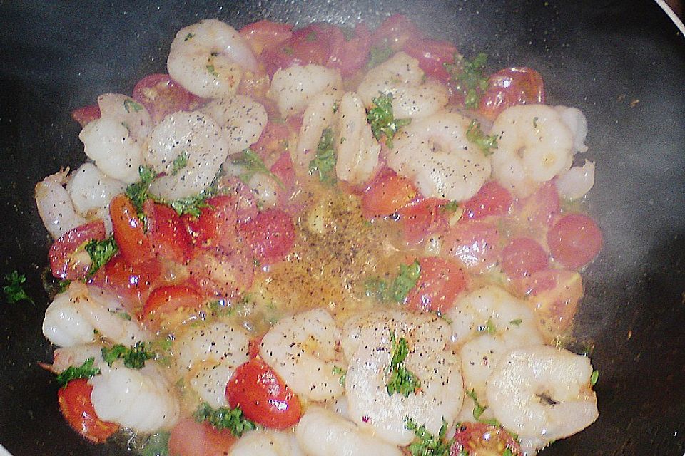 Bandnudeln Aglio e Olio mit Cocktailtomaten und Shrimps auf einem Bett aus Rucola