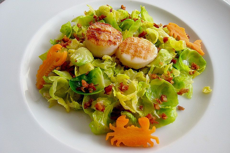 Jakobsmuschelnüsschen und Speckwürfel auf warmem Salat von Rosenkohlblättern