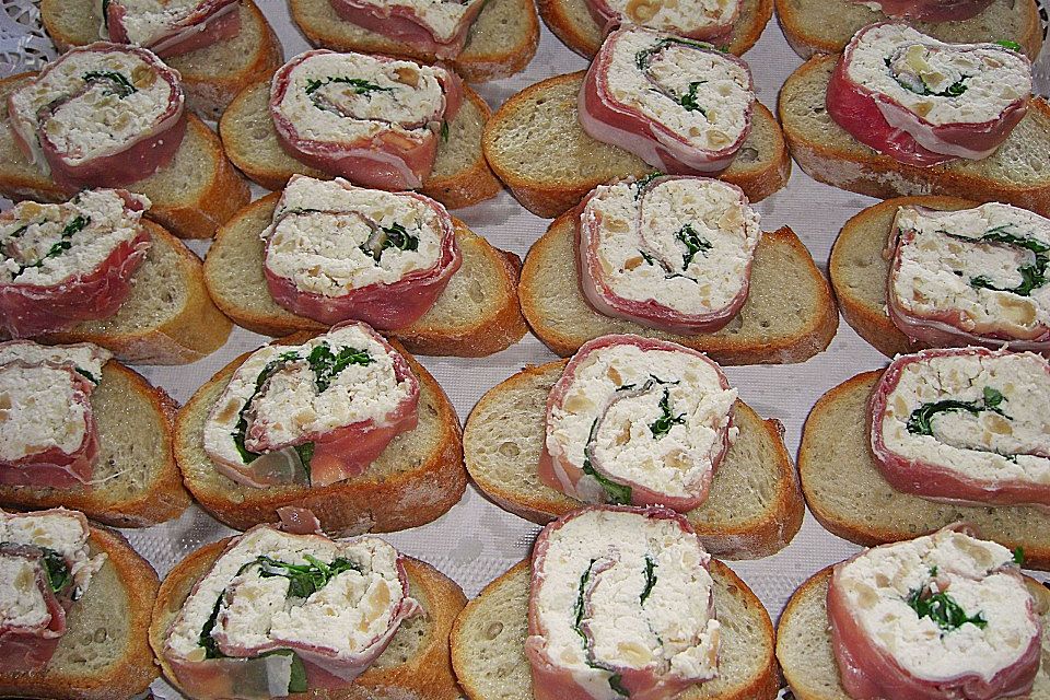 Parmaschinkenröllchen mit Frischkäse und Basilikum auf Röstbrotscheiben