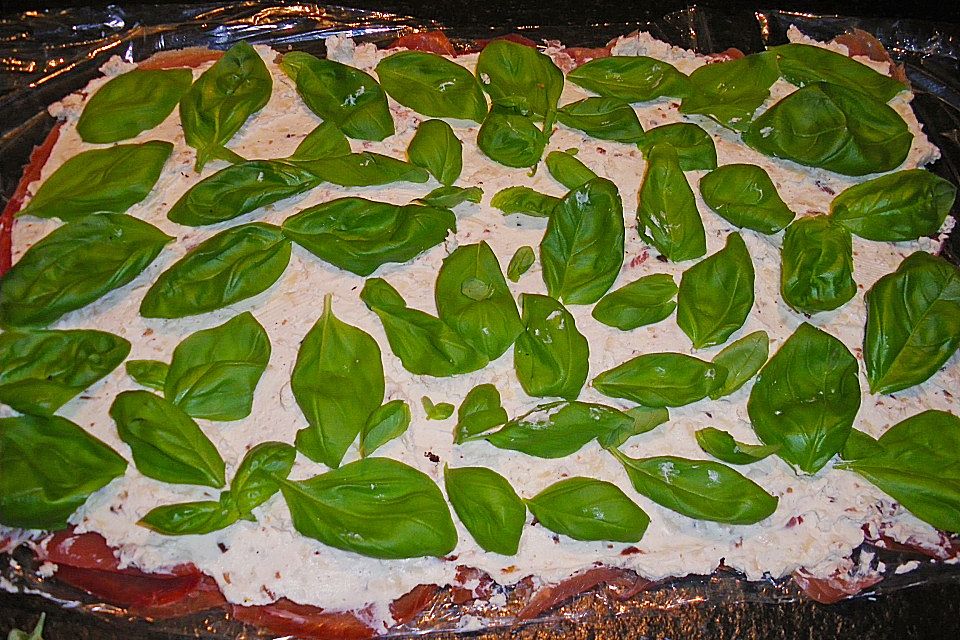 Parmaschinkenröllchen mit Frischkäse und Basilikum auf Röstbrotscheiben