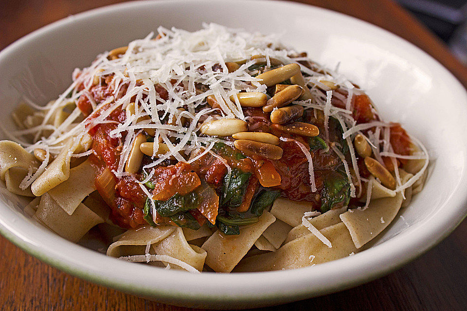 Pasta mit Tomatensauce auf frischen Blattspinat und Walnüssen