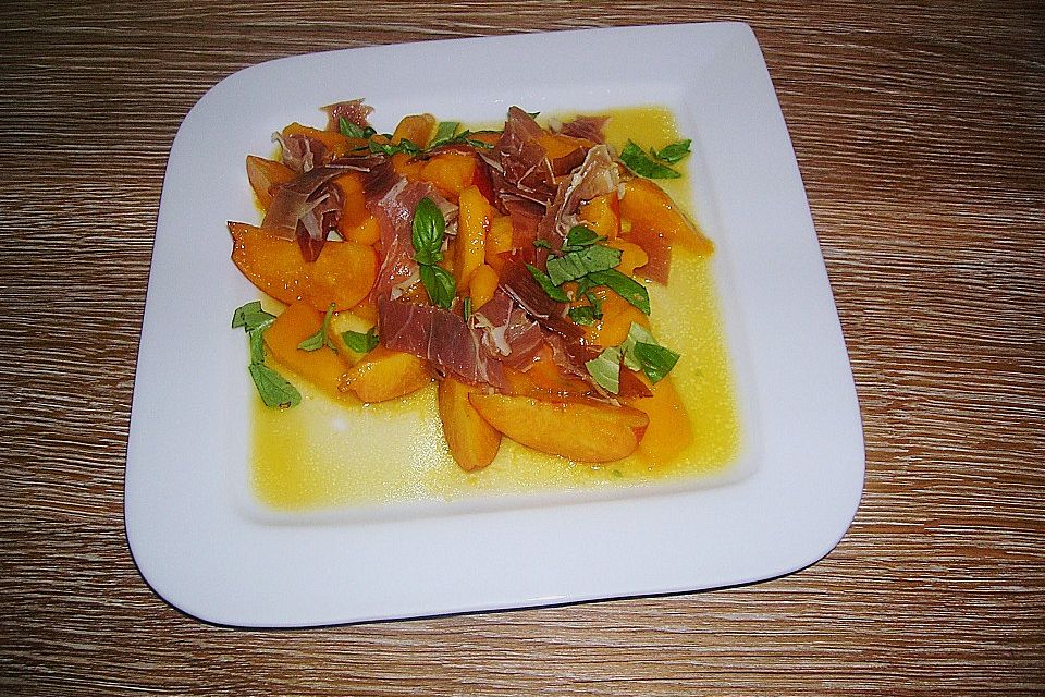 Fruchtsalat in orange mit Parmaschinken