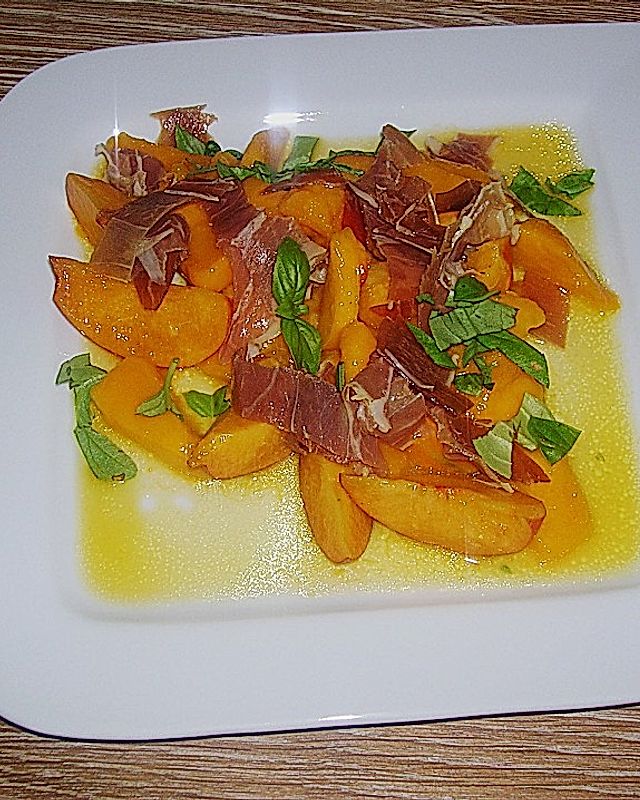 Fruchtsalat in orange mit Parmaschinken