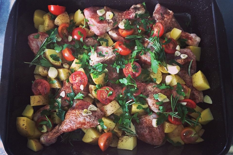 Knoblauch-Hühnchen mit Kartoffeln und Tomaten auf dem Backblech