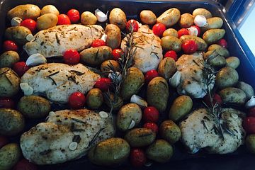 Knoblauch-Hühnchen mit Kartoffeln und Tomaten auf dem Backblech