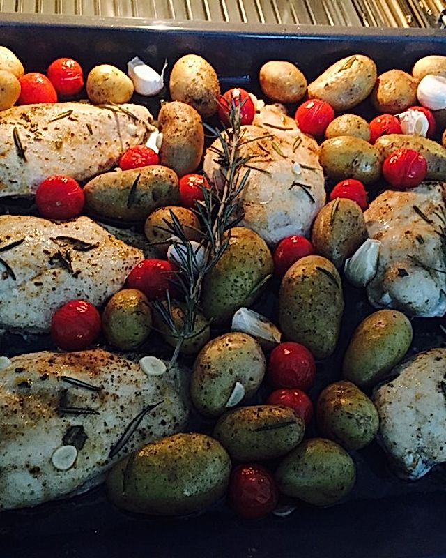 Knoblauch-Hühnchen mit Kartoffeln und Tomaten auf dem Backblech