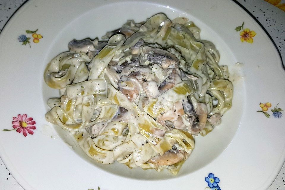 Grüne Bandnudeln mit frischen Champignons in einer Parmesan-Sahnesoße