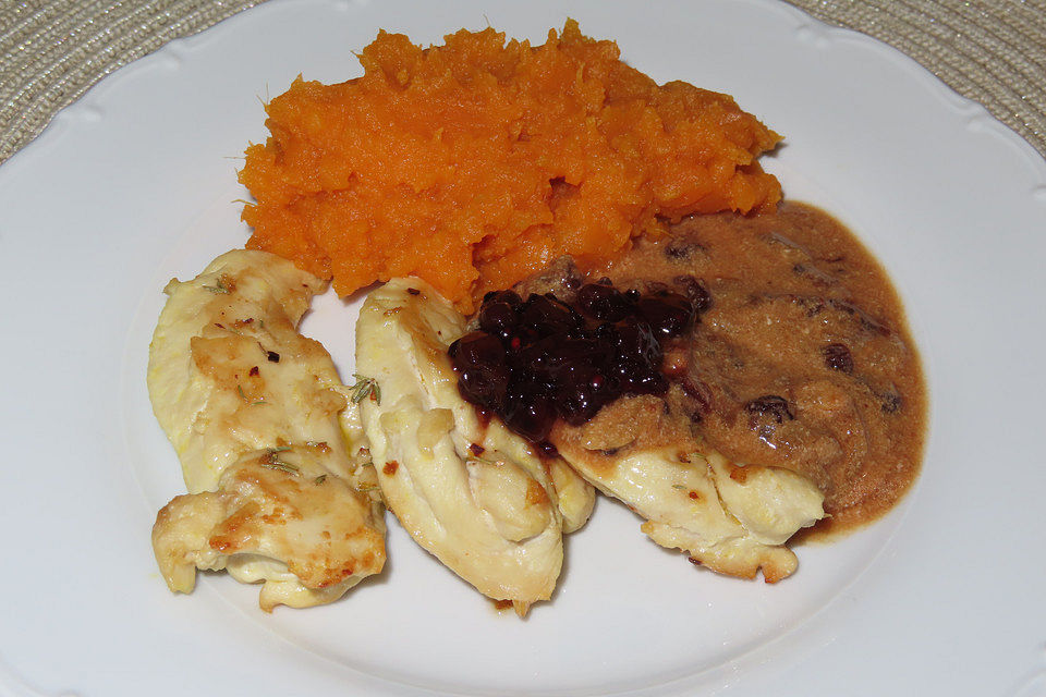 Gebratene Hähnchenfilets mit einer Soße mit Preiselbeeren und Süßkartoffelstampf