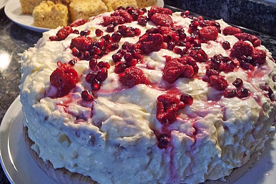 Weiße Schokoladentorte mit Mandelboden und Himbeeren und Granatapfel