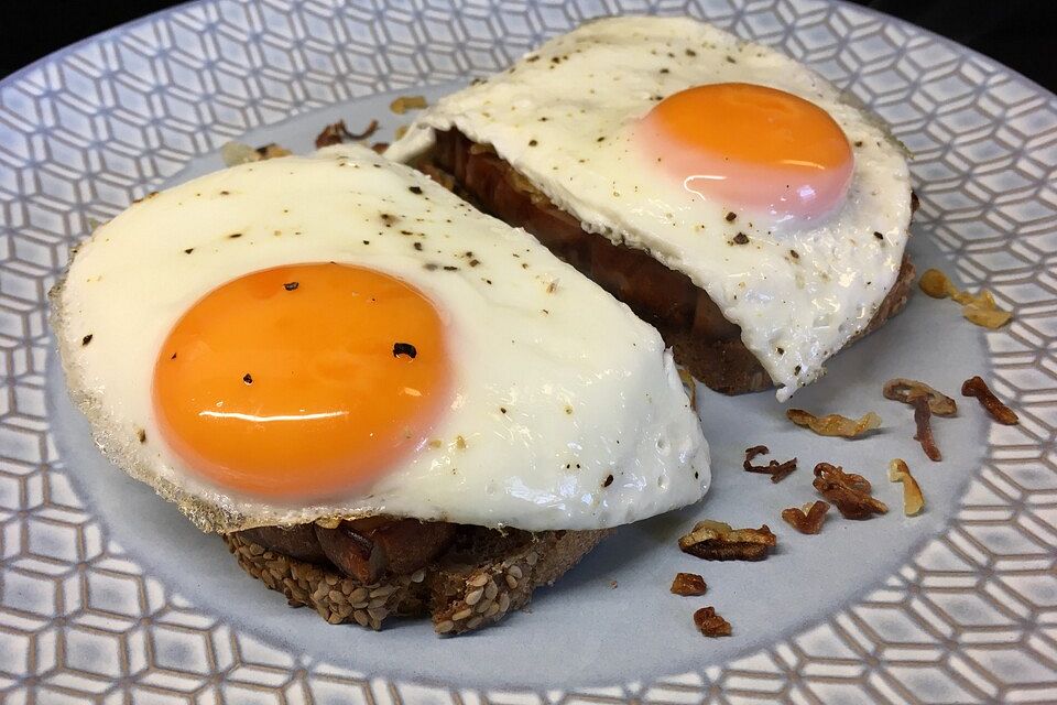 Fleischkäse mit Schalotten und Spiegelei auf Graubrot.