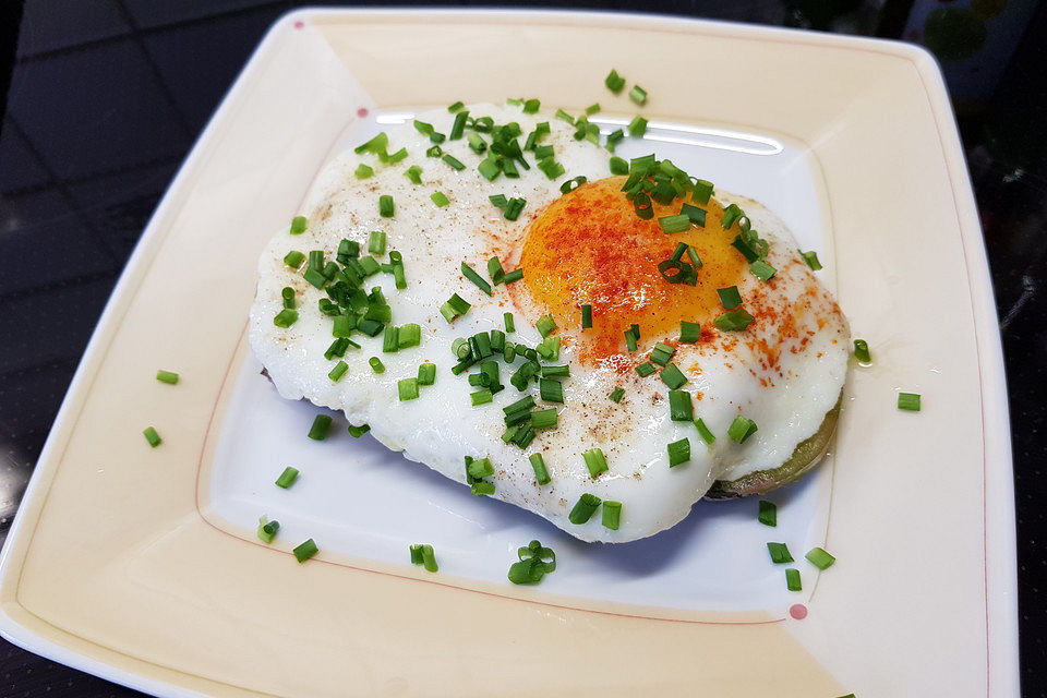 Gebratene Tomaten mit Zwiebelringen auf Bauernbrot mit Spiegeleiern