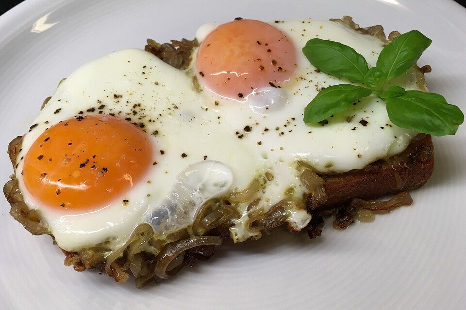 Spiegeleier auf Zwiebelringen und geröstetem Brot