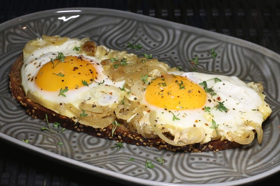 Spiegeleier auf Zwiebelringen und geröstetem Brot