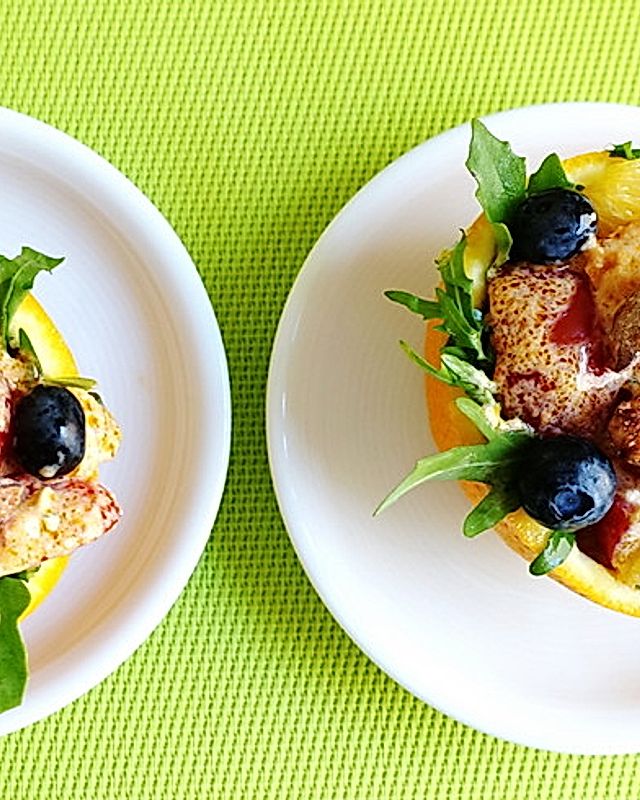 Frucht-Salat mit exotischem Dressing, in Orangenschalen serviert