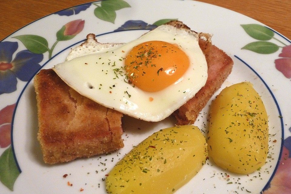 Panierter Leberkäse mit gedämpften Kartoffelhälften und Spiegeleiern