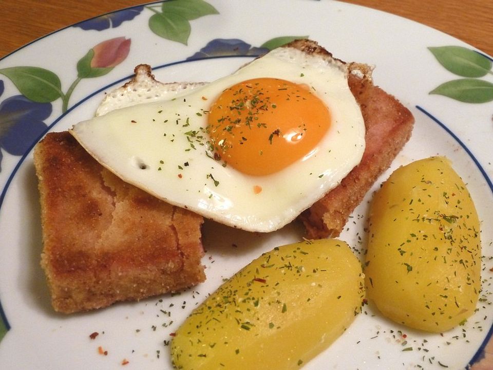 Panierter Leberkäse mit gedämpften Kartoffelhälften und Spiegeleiern ...