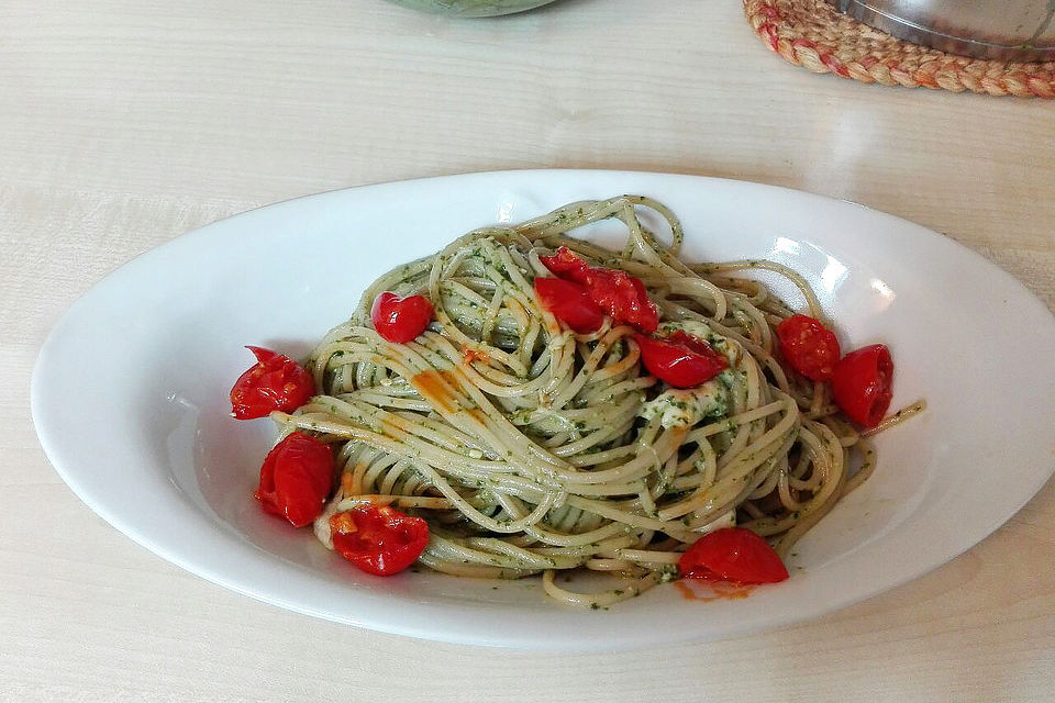 Vollkorn-Spaghetti mit frischem Basilikum-Pesto, dazu geschmolzene Tomaten und Mozzarella