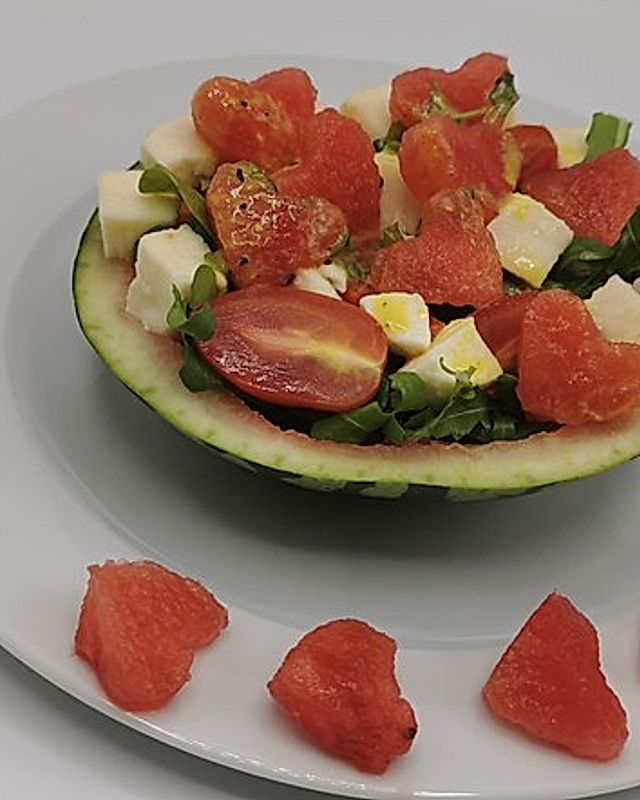 Wassermelonen-Mozzarella-Rucola-Salat mit Senfdressing und Pinienkernen, in der Melone serviert