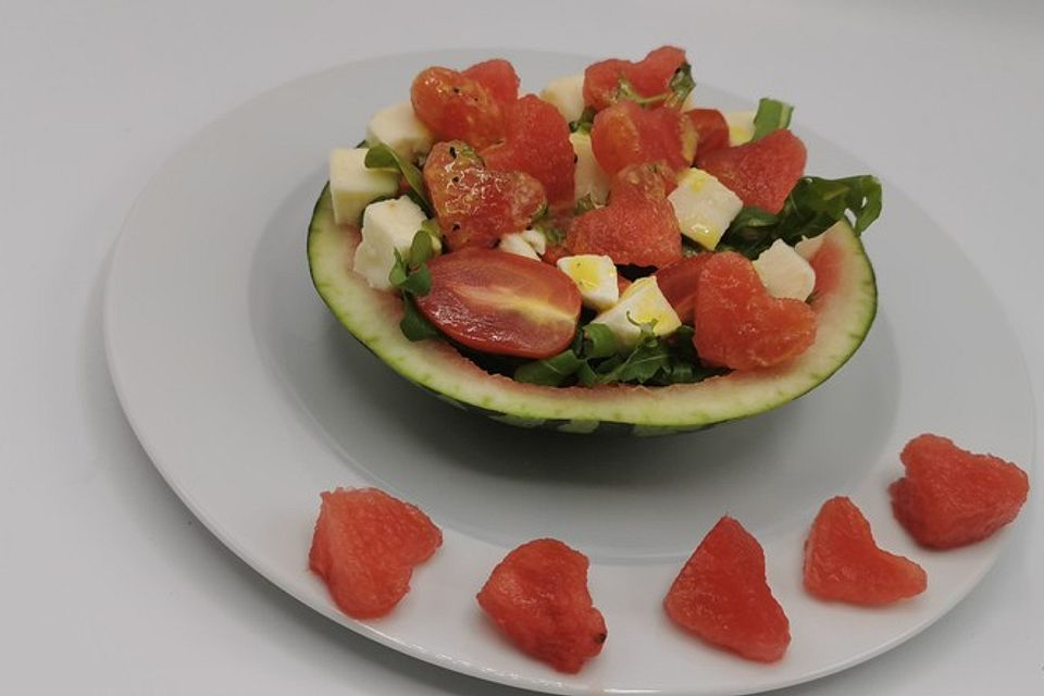 Wassermelonen-Mozzarella-Rucola-Salat mit Senfdressing und Pinienkernen, in der Melone serviert