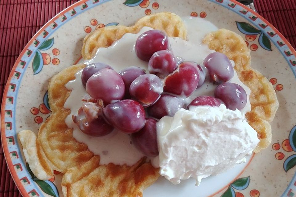 Frische Waffeln mit Puderzucker und heißen Kirschen