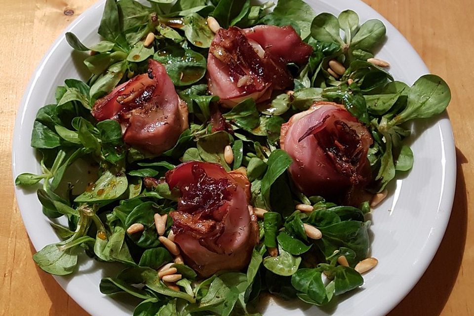 Ziegenkäsetaler mit Bacon, Apfelscheiben und karamellisierten Datteln auf Feldsalatbett mit Pinienkernen und Balsamico-Honig-Orangensaft-Senf-Dressing