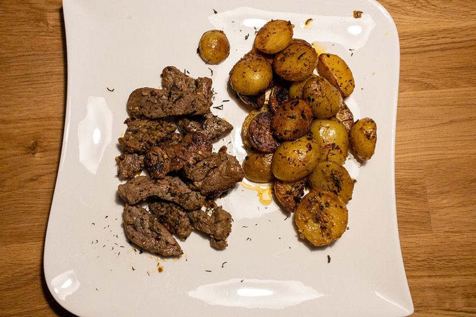 In Knoblauchbutter gebratene Steakstreifen mit Kartoffeln