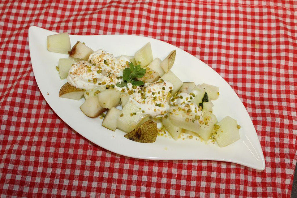 Piel de Sapo-Melone und Birne mit Honig-Joghurt und Pistazien sowie gerösteten Kokosflocken