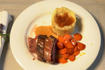 Rosa gegartes Kalbsfilet im Speckmantel an Rotweinsauce mit Kartoffel-Sellerie-Stampf und glasierten Möhren