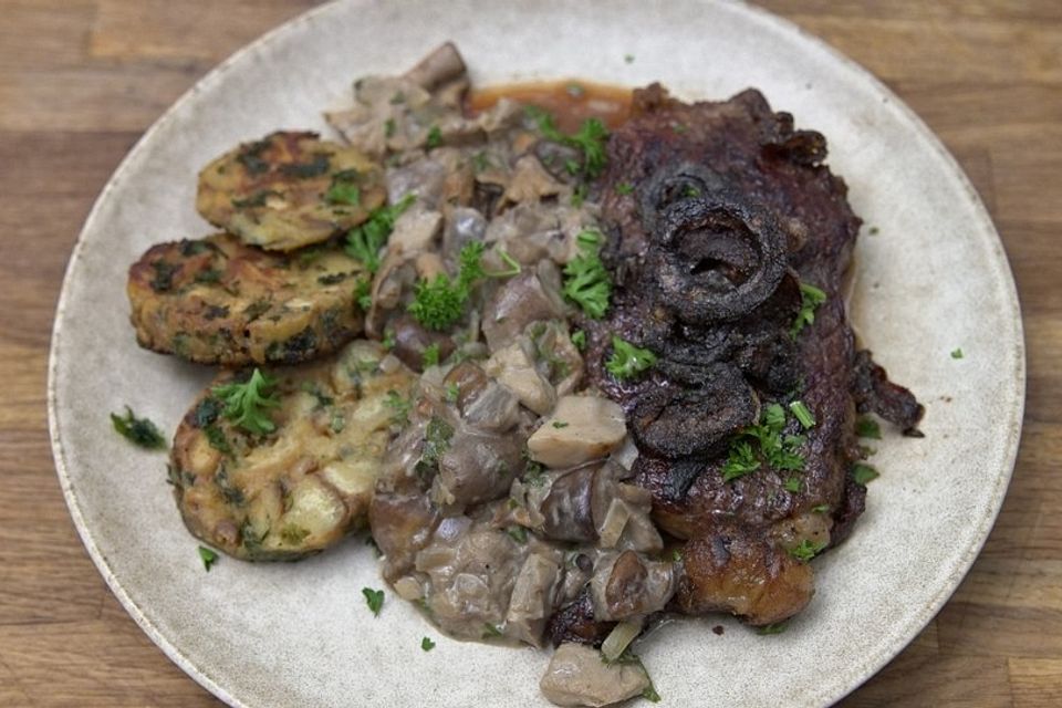 Zwiebelrostbraten mit frittierten Zwiebeln, Schwammerlsoße und in Petersilienbutter gebratenen Brezenknödeltranchen