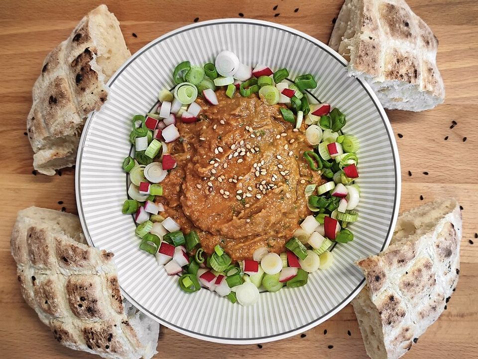 Avocado-Dip mit Kichererbsen, Tomaten und einem Frühlingszwiebel ...