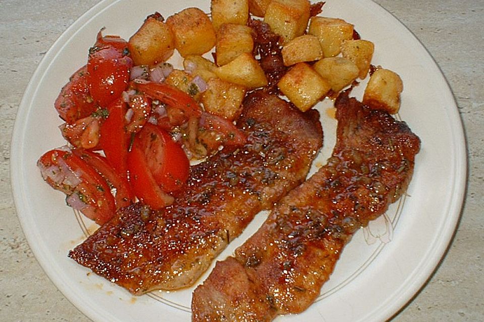 Schweineschnitzel mit Tomatensalat an groben Kartoffelwürfeln