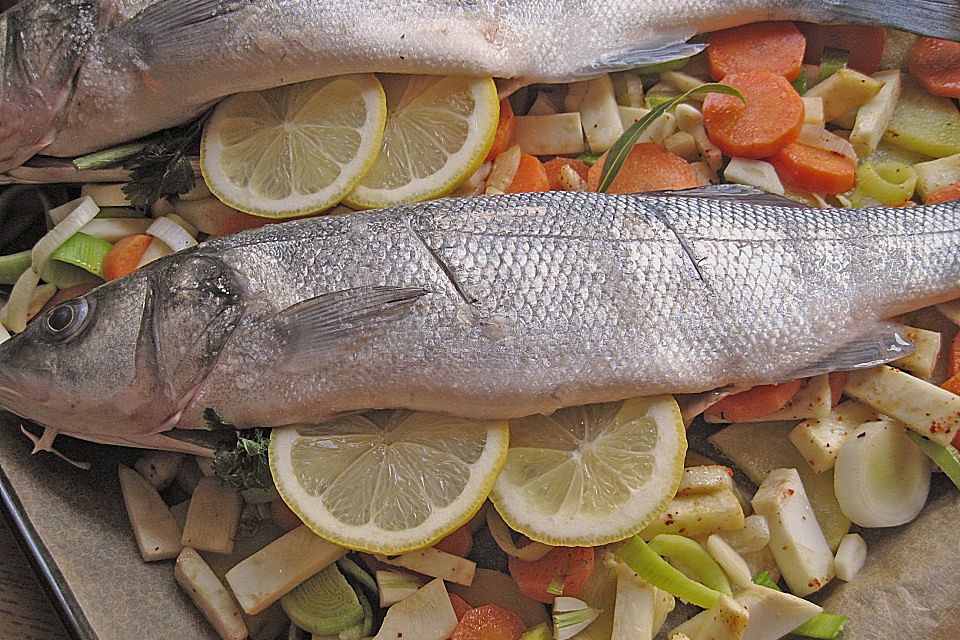 Ganzer Fisch auf Kartoffeln und Gemüse