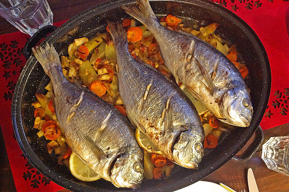 Ganzer Fisch auf Kartoffeln und Gemüse