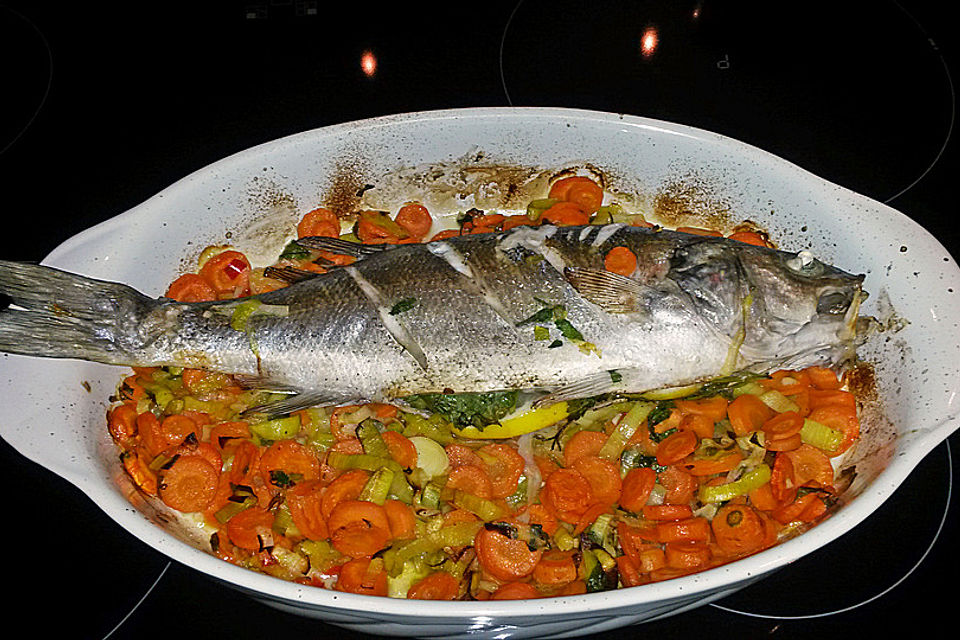 Ganzer Fisch auf Kartoffeln und Gemüse