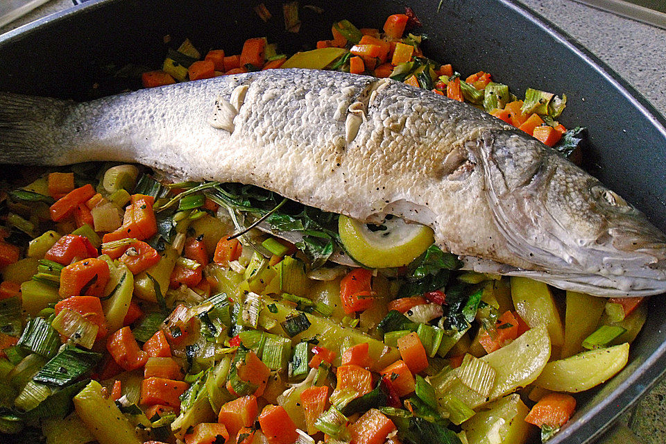 Ganzer Fisch auf Kartoffeln und Gemüse