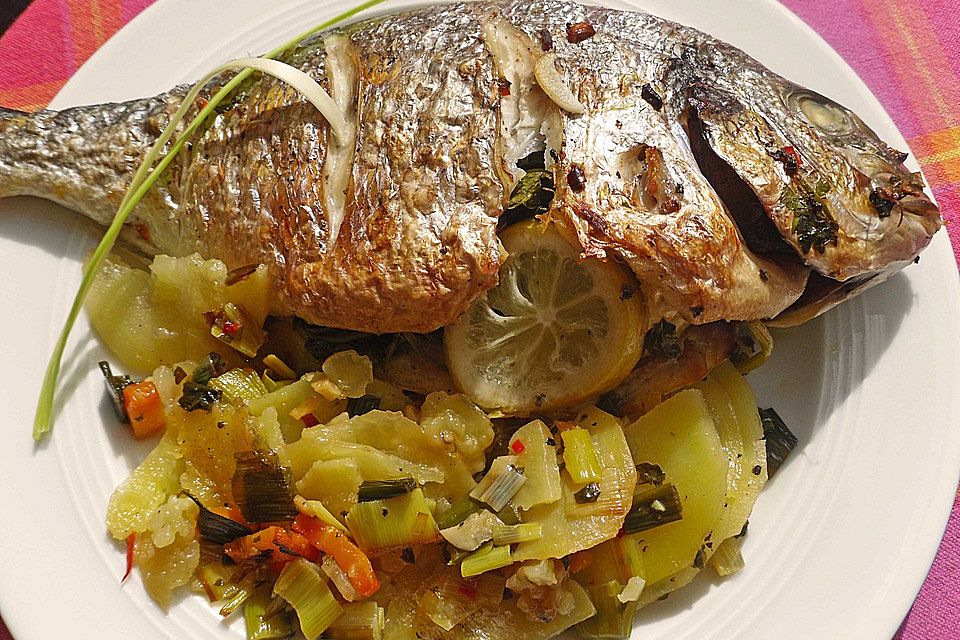 Ganzer Fisch auf Kartoffeln und Gemüse