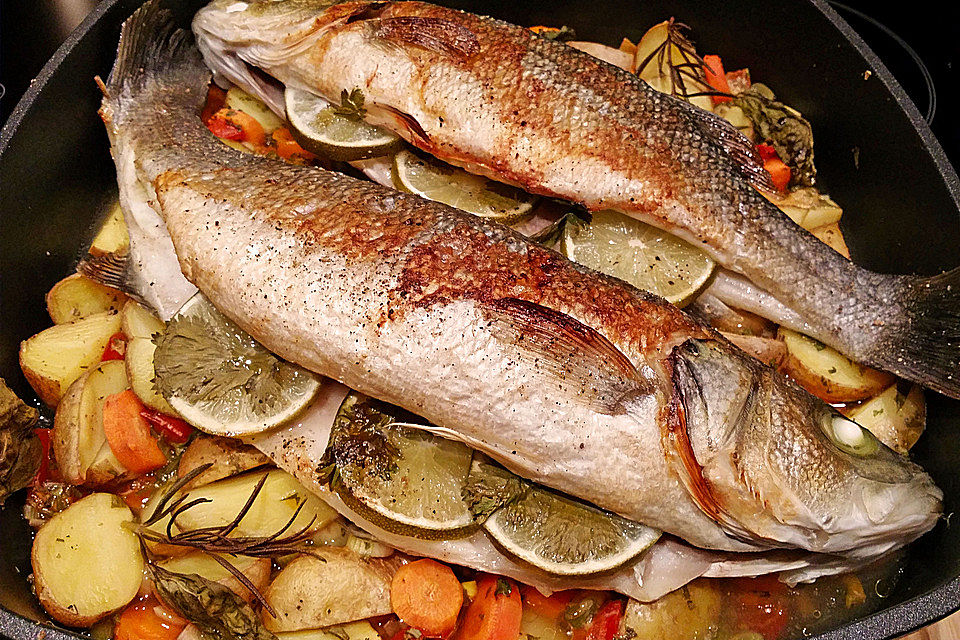 Ganzer Fisch auf Kartoffeln und Gemüse